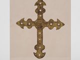 une croix dorée sur fond beige, posée sur un socle en bois