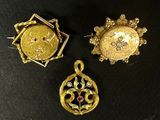 trois bijoux en or et diamants posés sur un fond noir