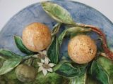 two oranges on a plate with leaves and flowers on it