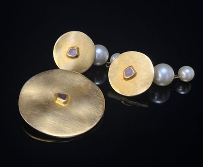 un gros plan sur une paire de boucles d'oreilles ornées de perles, posées sur un fond noir