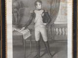 une vieille photo montrant un jeune garçon en costume, debout devant une table