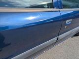 a blue truck parked in a parking lot next to a building