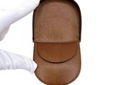a hand holding a brown case with a white glove