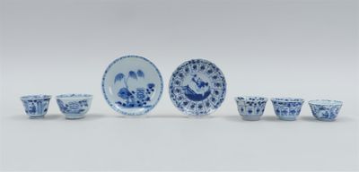 several blue and white dishes and cups are arranged on a white surface