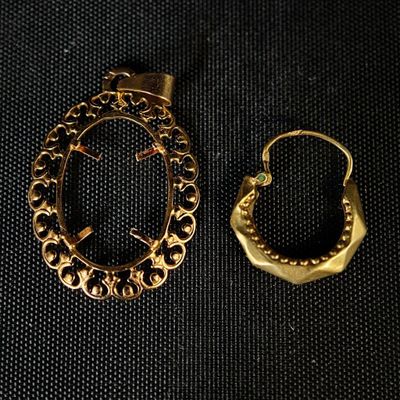 deux bijoux en or posés sur un tissu noir