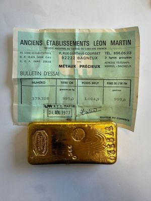 un lingot d'or posé à côté d'une feuille de papier