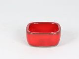 a small red bowl sitting on a white surface