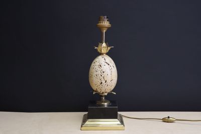 une photo d'une lampe de table blanche et dorée posée sur une table blanche