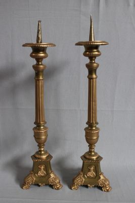 pair of antique brass candlesticks on a grey background