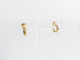 a close up of a pair of gold hoop earrings on a clear stand