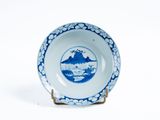 une assiette bleue et blanche sur laquelle est représentée une montagne