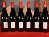 six bottles of red wine are lined up on a table