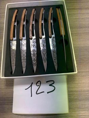 six knives in a box on a table with a price tag