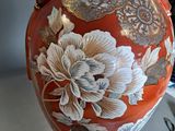 a red vase with gold and white flowers on it