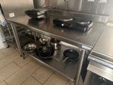 stainless steel counter top with pots and pans on it in a commercial kitchen