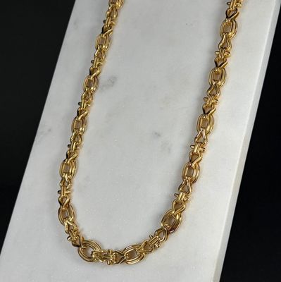 un gros plan d'un collier à chaîne en or posé sur une surface en marbre