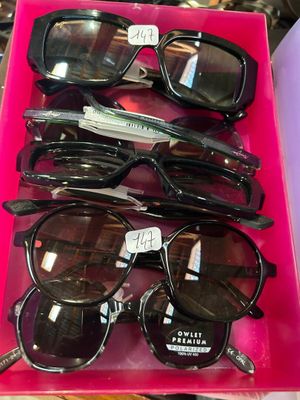 Plusieurs paires de lunettes de soleil se trouvent dans une boîte rose posée sur une table