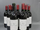 six bouteilles de vin rouge sont alignées sur une surface grise