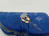 Gros plan sur une bague en or ornée d'une pierre bleue