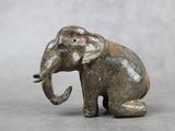 une statue d'éléphant assis par terre, la trompe tendue