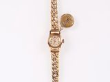 an image of a gold wrist watch with a leaf charm