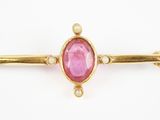 un gros plan d'une pierre rose sur une broche plaquée or