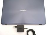 the asus laptop is sitting on a white surface with a charger plugged into it