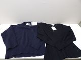 two sweaters are sitting on a white table in a room