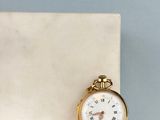 a gold pocket watch sitting on a marble block