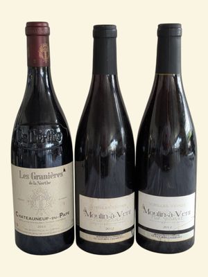 three bottles of wine are lined up on a white surface
