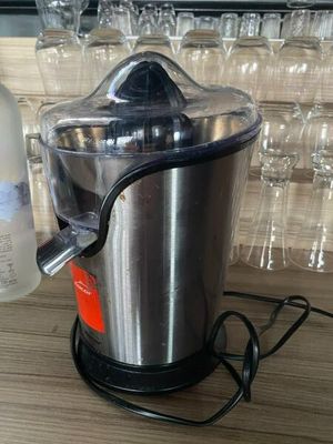 a silver juicer sitting on a table next to a bottle of vodka