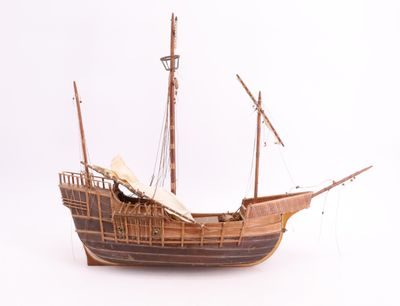 une maquette en bois d'un bateau posée sur une surface blanche