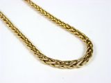 gros plan d'un collier en or sur une surface blanche