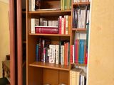 a bookshelf in the corner of a room with a door open