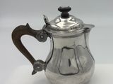 a silver tea pot with a wooden handle on a white surface