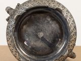 a silver plate with a bird on it sitting on a table