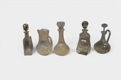 several glass vases and bottles are lined up on a white surface