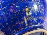 a blue vase with a gold decoration on it