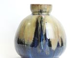 a blue and yellow vase sitting on a white surface