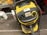 un aspirateur jaune et noir posé par terre dans un garage