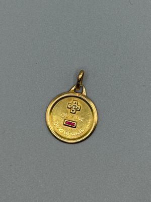 a close up of a gold coin with a small pink stone in the center
