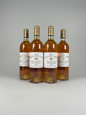 four bottles of wine are lined up on a white surface