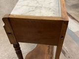an old wooden table with a marble top on wheels in a warehouse