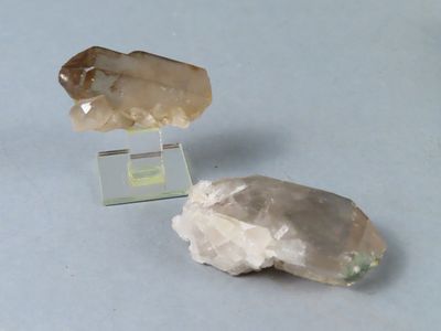 deux morceaux de quartz posés sur un socle en verre transparent, sur une table