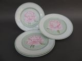 trois assiettes ornées de fleurs roses, posées sur une table