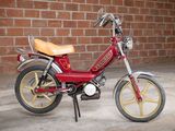 a small red motorcycle parked in front of a brick wall