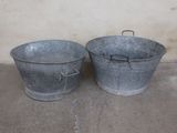 two metal buckets sitting next to each other on a cement floor