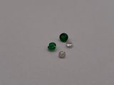 a pair of emerald and diamond earrings on a white surface