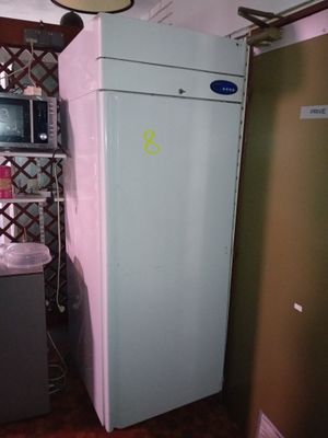 a refrigerator in a small kitchen with a microwave on top of it