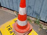 orange and white traffic cone sitting on top of a yellow and white sign